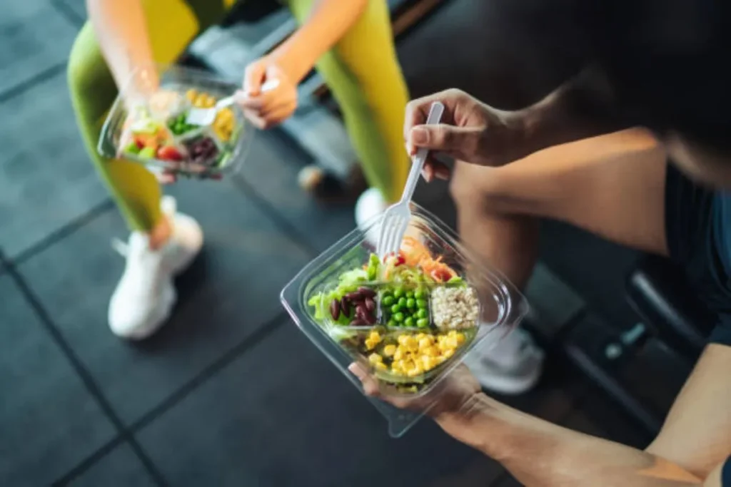 Two people holding salads in a gym
