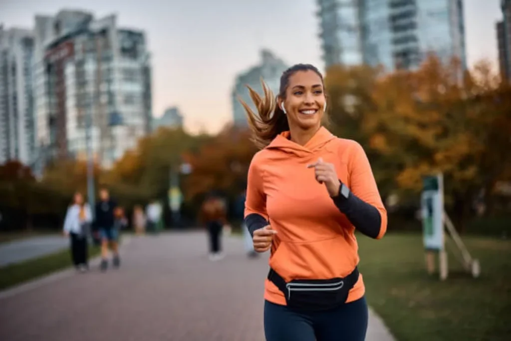 Woman in orange sportswear running with smile