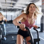 Femme souriante sur un vélo d'appartement dans une salle de sport
